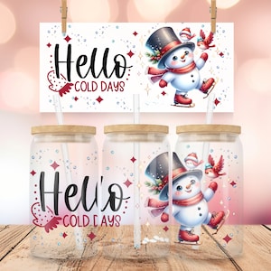 Pode incluir: Três copos de vidro transparente com tampas de madeira e canudos. Cada copo apresenta um boneco de neve patinando no gelo com dois pássaros, e o texto "Hello Cold Days".