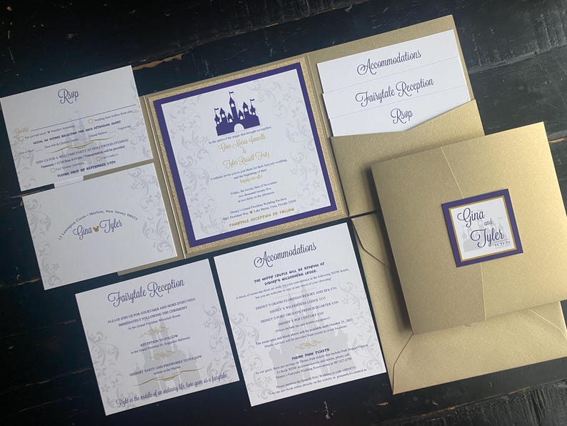 May include: Elegant wedding invitation suite with a gold and purple color scheme. The invitation features a castle silhouette and includes RSVP, reception, and accommodation details. The suite is presented on a dark wooden surface.