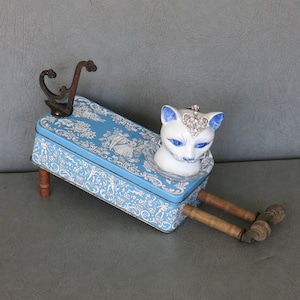 Cat assemblage, Isobel. Porcelain cat head, blue and white tin, industrial wood bobbins, castors, coat hook and rhinestone jewelry. afbeelding 1
