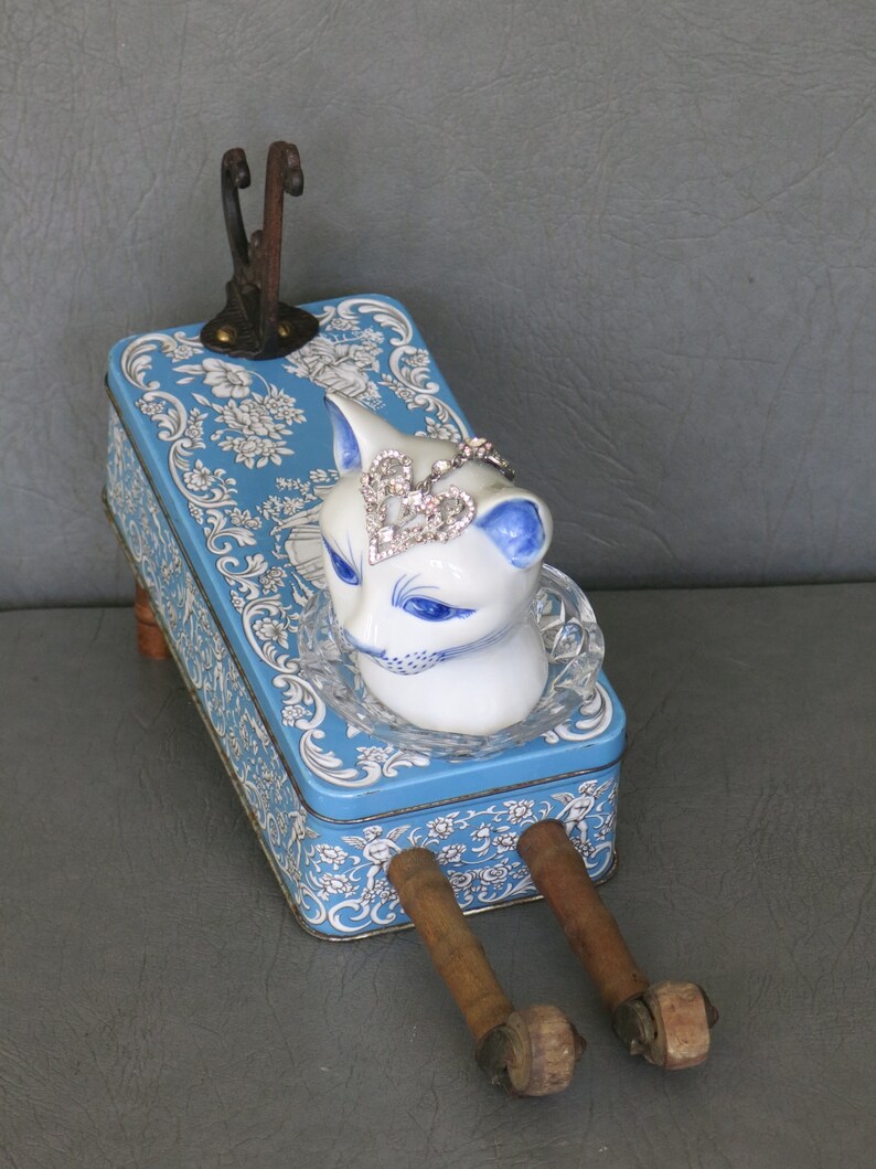 Cat assemblage, Isobel. Porcelain cat head, blue and white tin, industrial wood bobbins, castors, coat hook and rhinestone jewelry. image 3