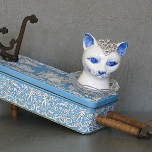 Cat assemblage, Isobel. Porcelain cat head, blue and white tin, industrial wood bobbins, castors, coat hook and rhinestone jewelry. image 2