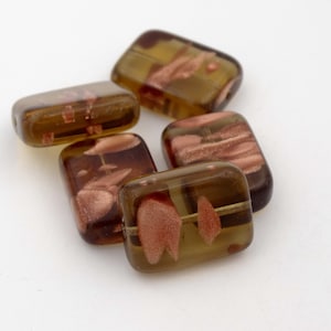 Könnte beinhalten: Sechs rechteckige Glasperlen. Die Perlen sind in einem transparenten Olivgrün mit rotbraunen Mustern gehalten. Jede Perle hat abgerundete Kanten und ein Loch zum Auffädeln, ideal für Schmuck.