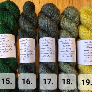 May include: Five skeins of British Shetland wool yarn in shades of green and yellow. Each skein is labeled with weight, length, and yarn weight. The colors range from deep forest green to a bright, chartreuse yellow.