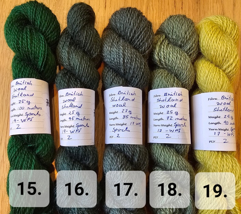 May include: Five skeins of British Shetland wool yarn in shades of green and yellow. Each skein is labeled with weight, length, and yarn weight. The colors range from deep forest green to a bright, chartreuse yellow.