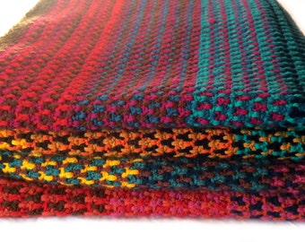 Puede incluir: Una pila de cuatro mantas de ganchillo en una variedad de colores, incluyendo rojo, naranja, amarillo, verde, azul y marrón.