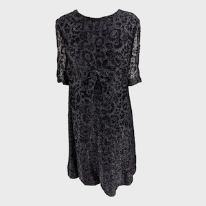 May include: A black short-sleeved dress with a floral pattern. The dress has a scoop neck and a fitted bodice.