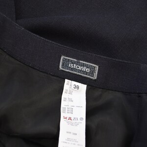 Puede incluir: Una falda negra con una etiqueta blanca que dice "Istante Versace" y tiene la talla 38. La etiqueta tambi&eacute;n incluye la composici&oacute;n del tejido: 70% seda, 30% lana, 70% seda, 30% lana, 100% ray&oacute;n, 100% ray&oacute;n, 100% ray&oacute;n. La etiqueta tambi&eacute;n incluye instrucciones de cuidado: limpieza en seco profesional, no blanquear, no secar en secadora, planchar en caliente.