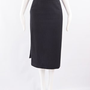 Puede incluir: Una falda midi negra con una abertura lateral. La falda est&aacute; hecha de una tela lisa y texturizada.