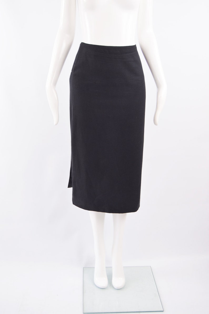 Puede incluir: Una falda midi negra con una abertura lateral. La falda est&aacute; hecha de una tela lisa y texturizada.