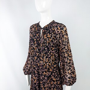May include: A long-sleeved dress with a brown, black, and pink animal print. The dress has a gathered neckline and a loose fit.