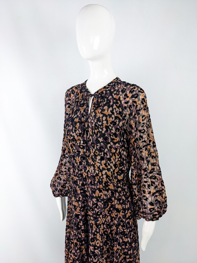 May include: A long-sleeved dress with a brown, black, and pink animal print. The dress has a gathered neckline and a loose fit.