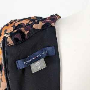 May include: A black dress with a leopard print bodice and a black velvet trim. The dress has a zipper closure and a tag that reads "Tommy Hilfiger" and "made in China 12".