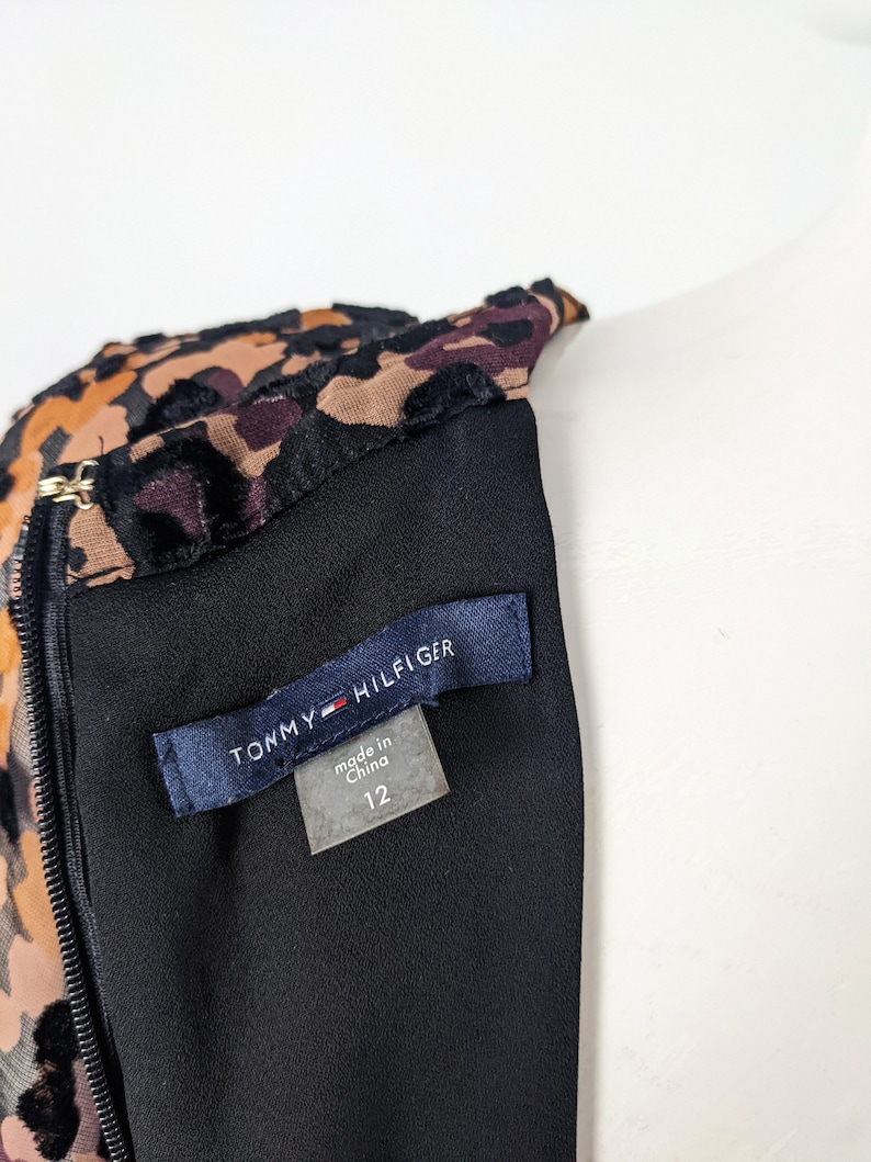 May include: A black dress with a leopard print bodice and a black velvet trim. The dress has a zipper closure and a tag that reads "Tommy Hilfiger" and "made in China 12".