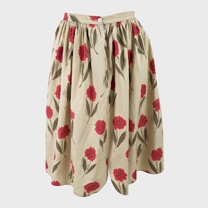 May include: A beige skirt with a red floral print. The skirt has a gathered waist and a full, flowing silhouette.