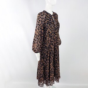 May include: A long-sleeved midi dress with a leopard print pattern in shades of brown, black, and pink. The dress has a gathered skirt and a tie at the neckline.