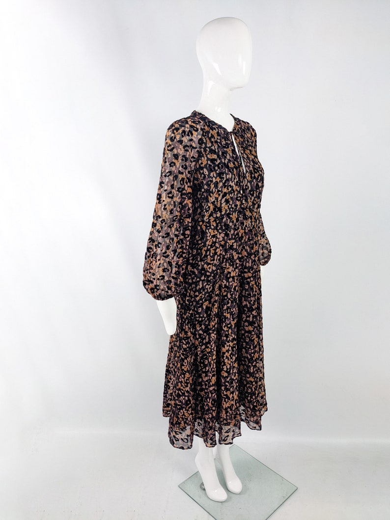 May include: A long-sleeved midi dress with a leopard print pattern in shades of brown, black, and pink. The dress has a gathered skirt and a tie at the neckline.