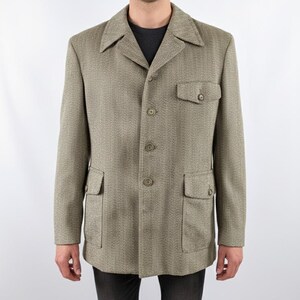 May include: A tan herringbone blazer with a notched collar, three buttons, and two front pockets. The blazer has long sleeves and a classic, tailored fit. The jacket is made of a textured fabric.