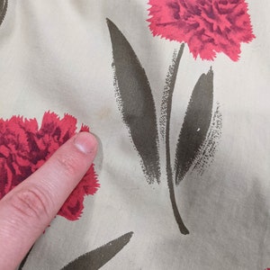 May include: Beige fabric with a repeating pattern of red carnations and dark green leaves.