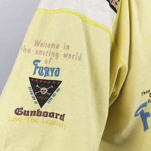 May include: Yellow short-sleeved t-shirt with a graphic print of a skull and crossbones with the text "Welcome in the amazing world of Furyo" and "Gunboard Live The Legend!"