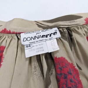 May include: A beige cotton fabric with a floral print of red and brown flowers. The fabric has a label that reads "Graziella Ronchi per Donnaerre Made in Italy - Milano 44 de in Italy 100% Cotone Cotton".