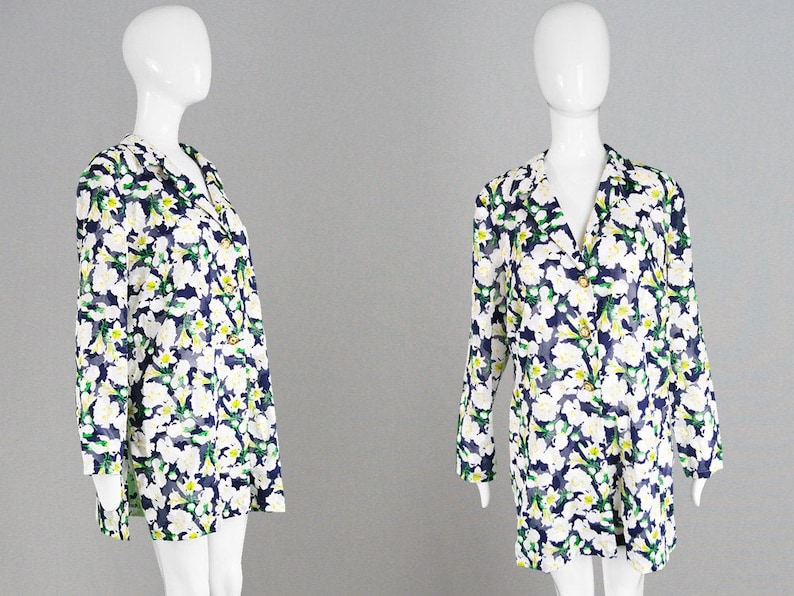 Pu&ograve; includere: Una giacca blu scuro a maniche lunghe con stampa floreale bianca e verde. La giacca ha un colletto e una chiusura con bottoni.