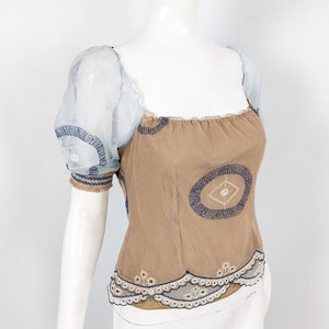May include: A brown and blue embroidered top with a sheer blue overlay on the sleeves. The top has a square neckline and a scalloped hem.