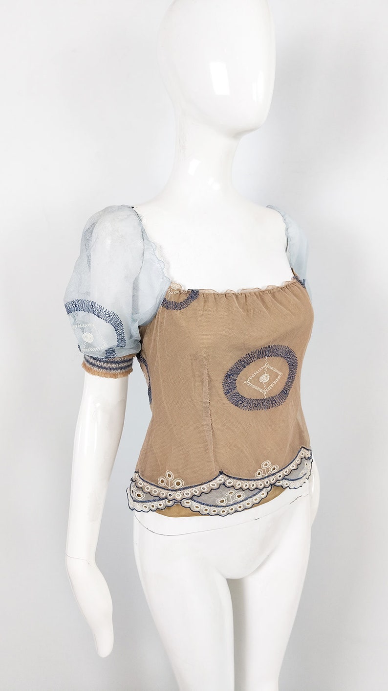 May include: A brown and blue embroidered top with a sheer blue overlay on the sleeves. The top has a square neckline and a scalloped hem.