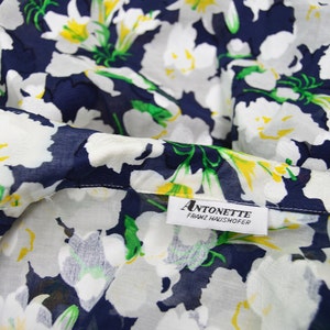 Pu&ograve; includere: Tessuto floreale bianco su sfondo blu navy. Il tessuto ha un'etichetta che recita "ANTONETTE FRANZ HAUSHOFER".