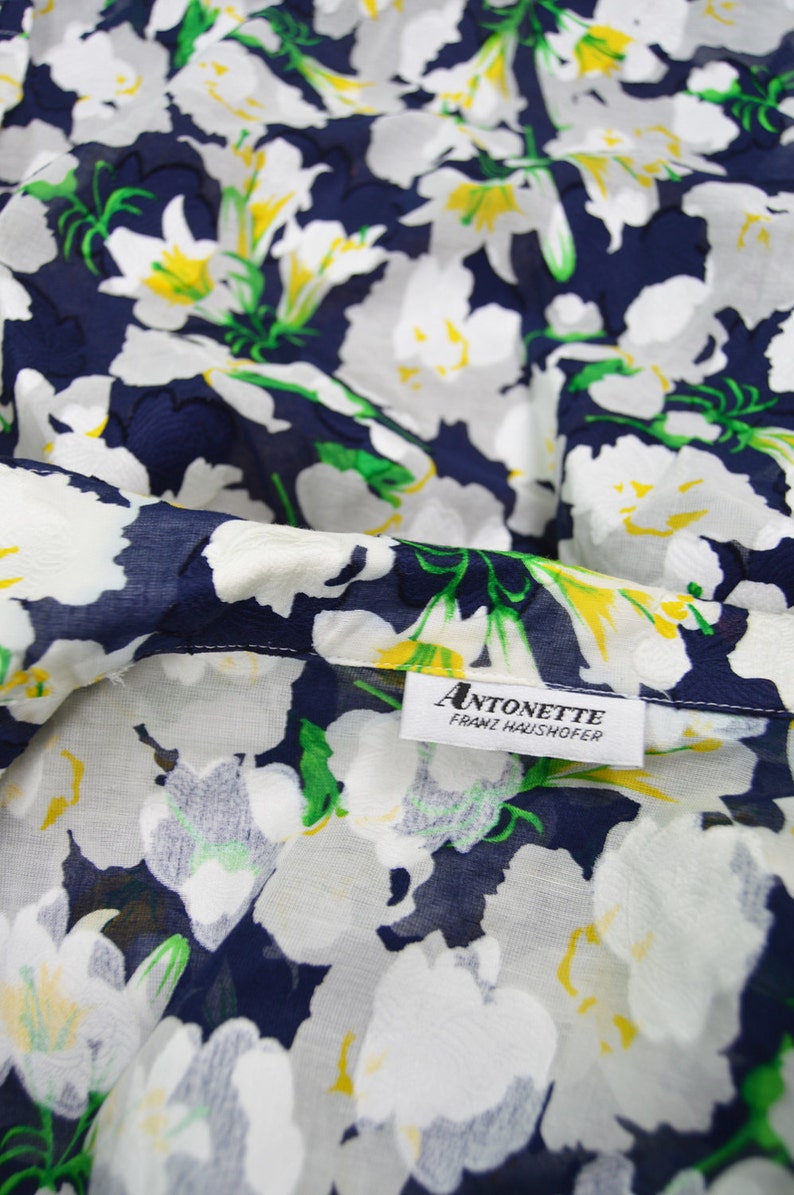 Pu&ograve; includere: Tessuto floreale bianco su sfondo blu navy. Il tessuto ha un'etichetta che recita "ANTONETTE FRANZ HAUSHOFER".