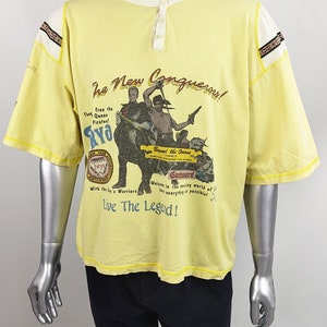 May include: Yellow t-shirt with a graphic print of pirates and the text "The New Conquerous!"  "They free the Queen Pirates! RYO"  "Beyond the Oceans There is Something Stranger Than Storms"  "Gunboard"  "Welcome in the exciting world of fun everything is possible!"  "Live The Legend!"