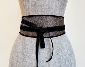 May include: A wide black leather belt with a silver shimmer finish. The belt is tied in a bow at the front.