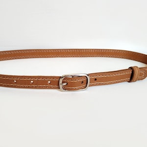 May include: A brown leather belt with a silver buckle and white stitching.