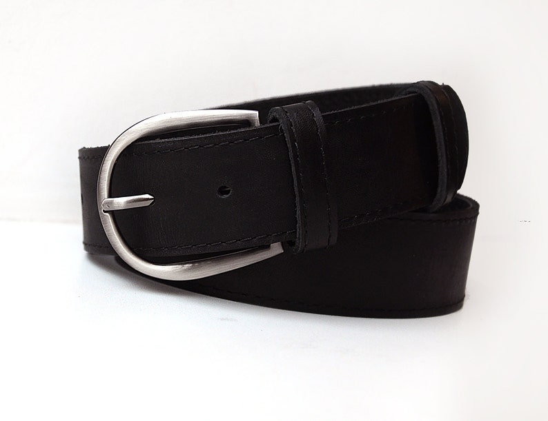 May include: A black leather belt with a silver buckle. The belt is rolled up and the buckle is visible.