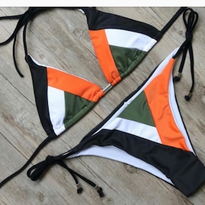 May include: A black, white, orange, and green bikini with adjustable straps. The bikini top is a triangle style and the bottom is a cheeky cut.