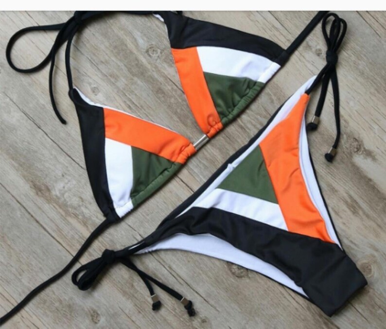 May include: A black, white, orange, and green bikini with adjustable straps. The bikini top is a triangle style and the bottom is a cheeky cut.