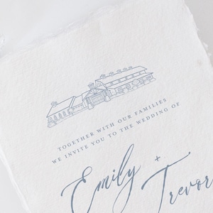Puede incluir: Una invitación blanca con una ilustración azul de un edificio y texto. El texto dice "Together with our families, we invite you to the wedding of Emily + Trevor" en una fuente manuscrita.