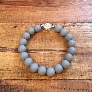May include: A gray beaded bracelet with a silver and crystal accent.
