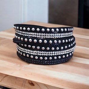 May include: A black leather wrap bracelet with silver studs and clear rhinestones.