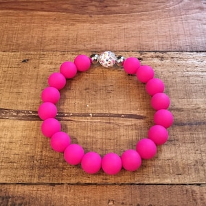 May include: A pink silicone bracelet with a silver and crystal bead.