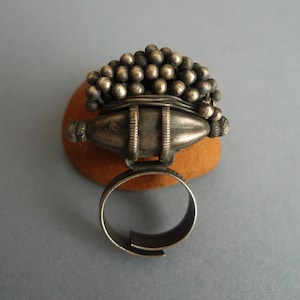 May include: A silver ring with a large, round, beaded top and a simple band. The beads are arranged in a dome shape and are all the same size.