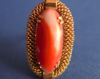 May include: A gold ring with a red and white oval shaped stone set in a woven wire design.