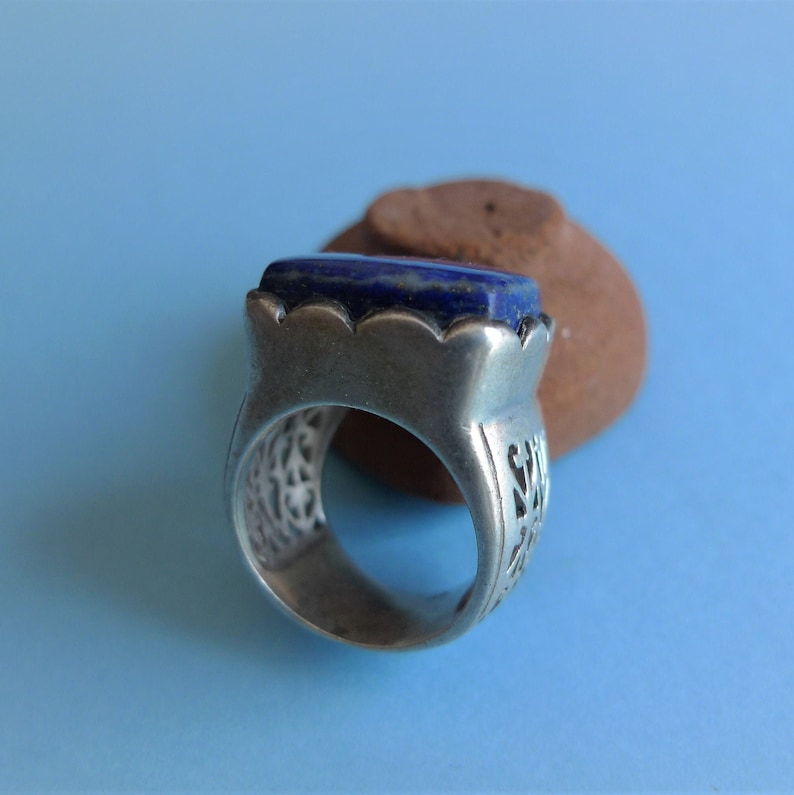 May include: A silver ring with an intricate design and a blue lapis lazuli stone.