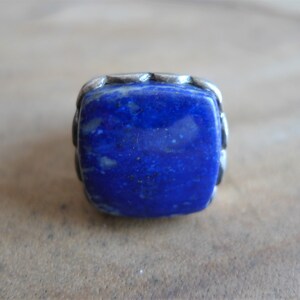 May include: A square-shaped ring with a deep blue lapis lazuli stone set in a silver band.