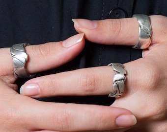 Könnte beinhalten: Ein Satz von drei silbernen Ringen mit einem strukturierten Design. Die Ringe werden an den Fingern einer Hand getragen.