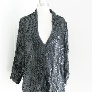 May include: A black sequined jacket with a V-neck and a button closure.