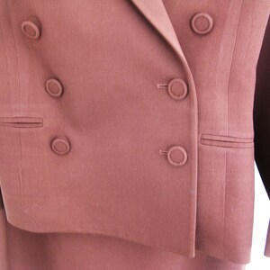 Pu&ograve; includere: Un blazer marrone doppiopetto con cinque bottoni. Il blazer &egrave; realizzato in un tessuto liscio e testurizzato.