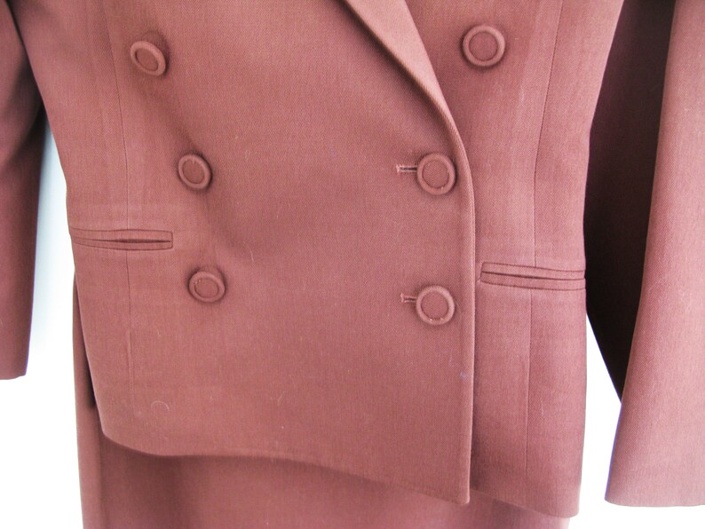 Pu&ograve; includere: Un blazer marrone doppiopetto con cinque bottoni. Il blazer &egrave; realizzato in un tessuto liscio e testurizzato.