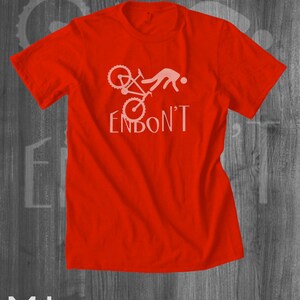 May include: Red t-shirt with a white graphic of a person falling off a bicycle with the text "ENBON'T".