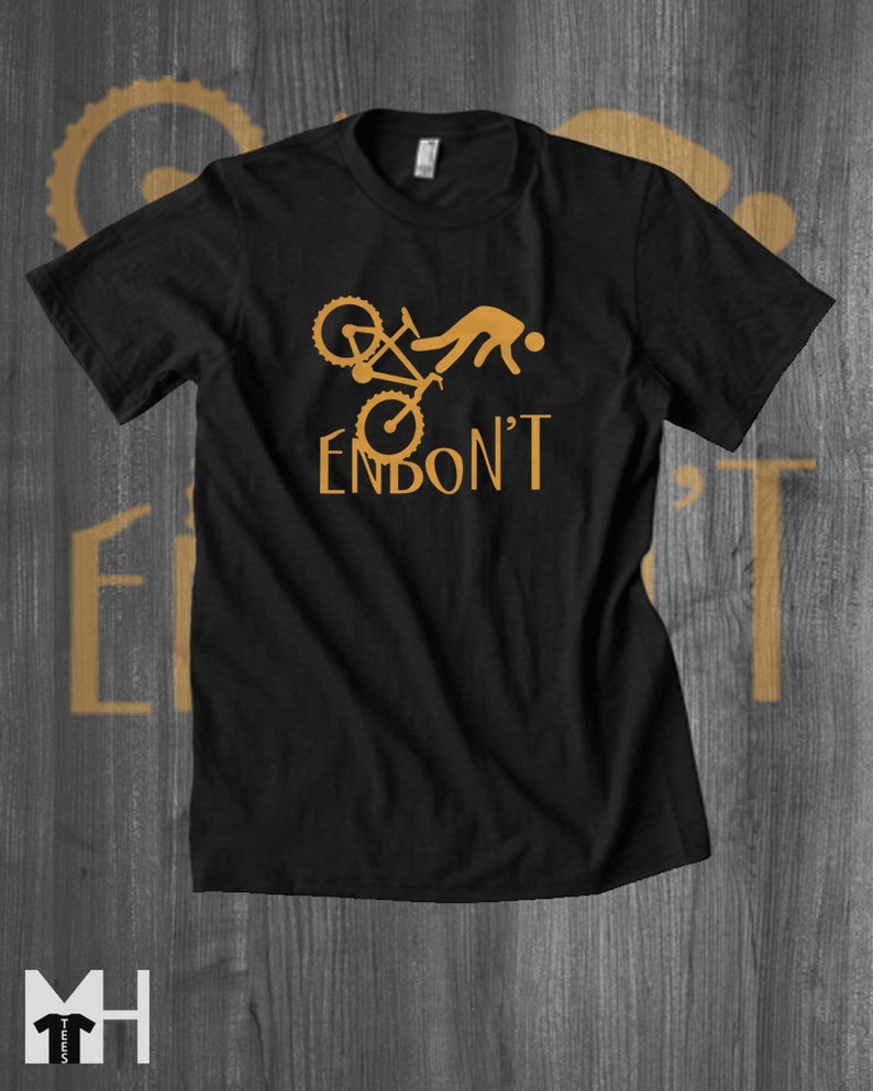 May include: Black t-shirt featuring a graphic of a person falling off a bicycle with the text "Endon't" in gold.