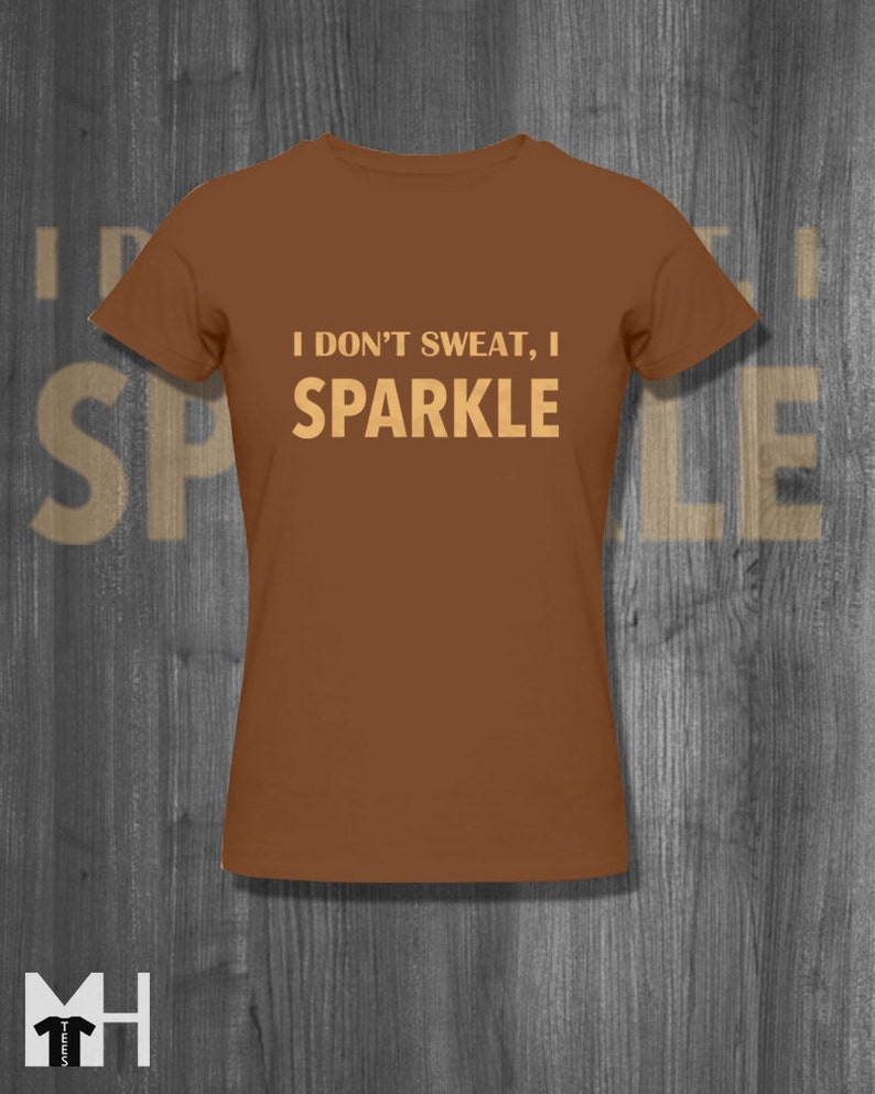May include: A brown t-shirt with the text "I don't sweat, I sparkle" in a light brown colour.